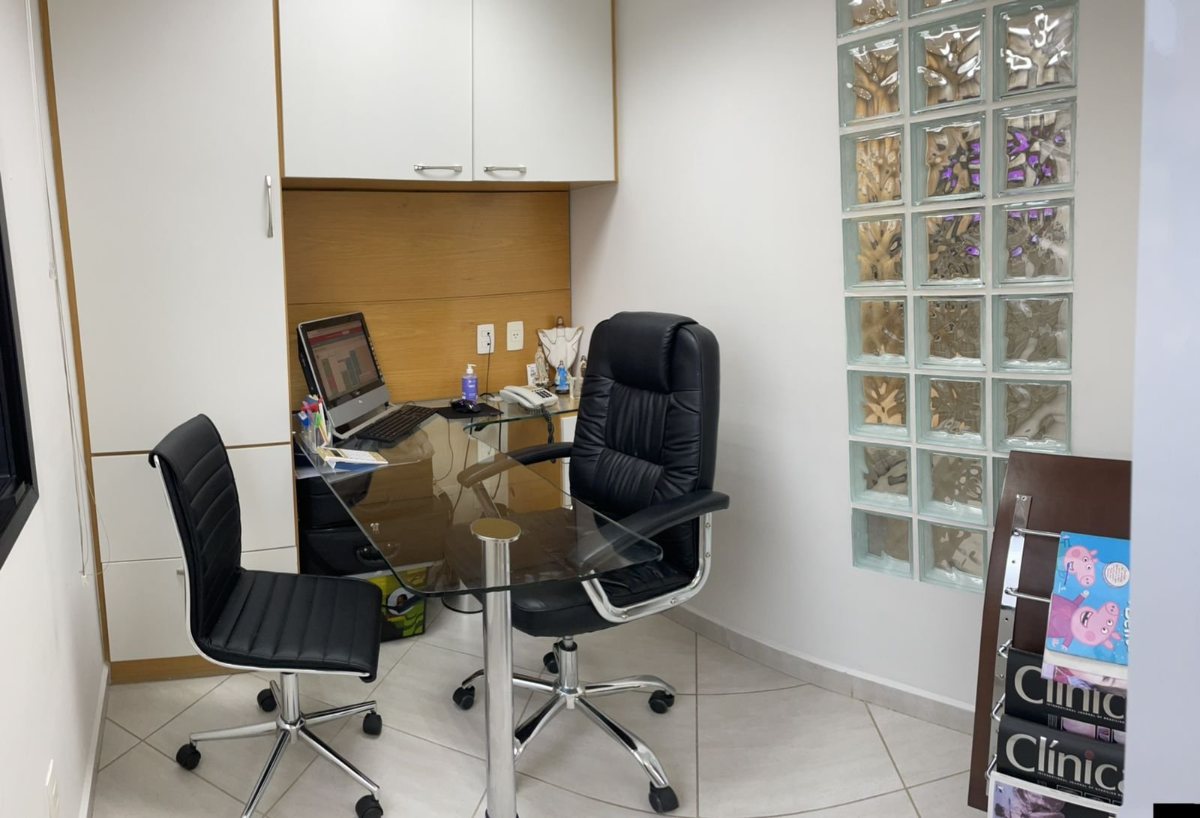 Sala de conversa com mesa de vidro, cadeiras e parede de tijolos de vidro